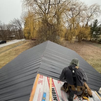 Standing seam metal panels being installed at ridge