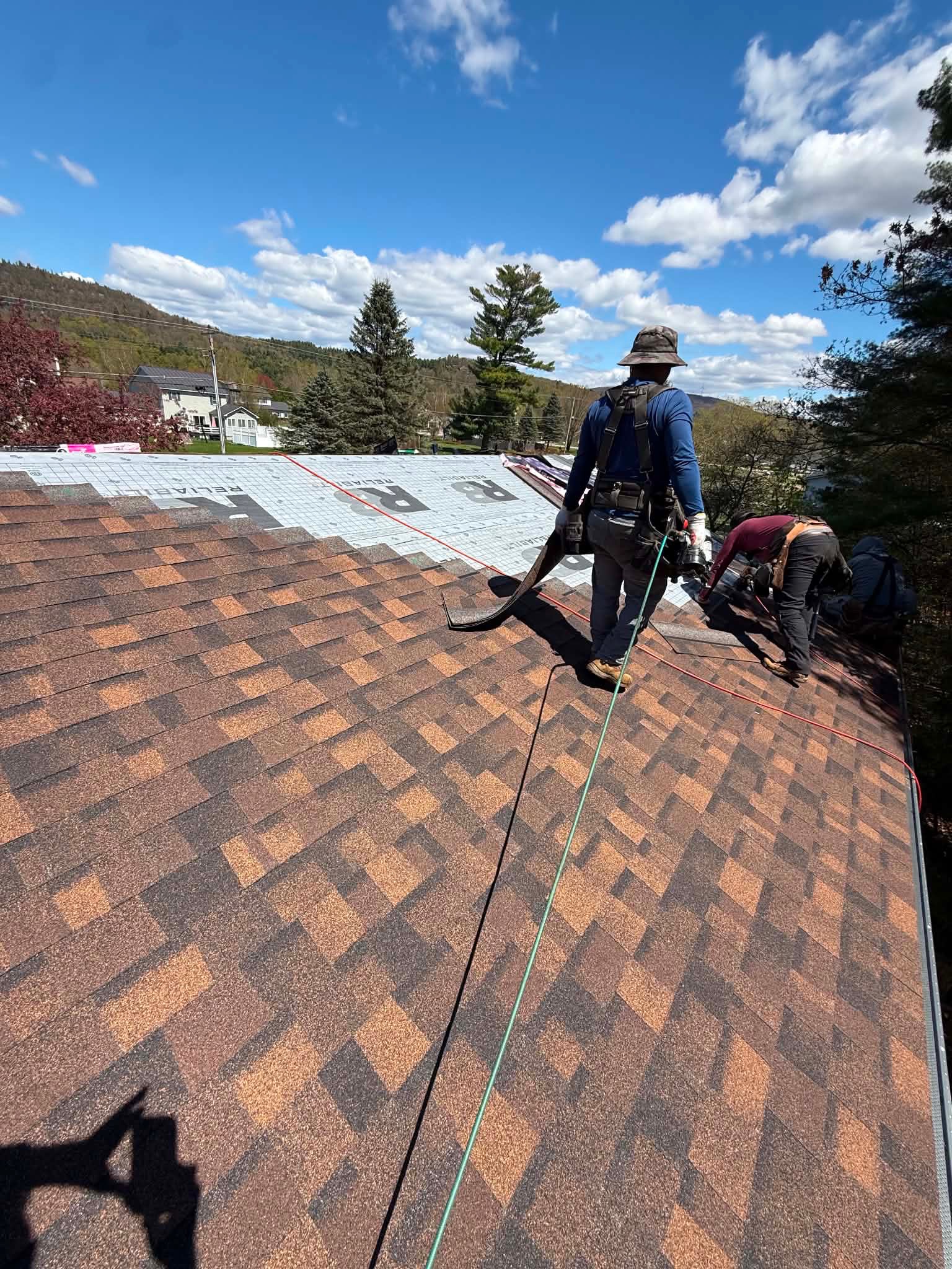 Crew laying shingles with harnesses on